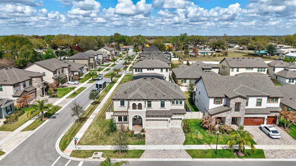 An aerial view shows a suburban neighborhood with multi-story houses, paved driveways, and green lawns — 4593 SHORELEAF LOOP, VALRICO, FL