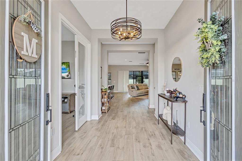 A bright entryway features light wood-look flooring, a modern circular chandelier, and a console table — 4593 SHORELEAF LOOP, VALRICO, FL