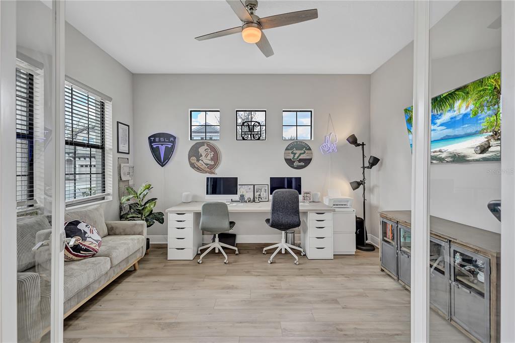A home office features a dual-desk setup, a gray sofa, and light wood-look flooring — 4593 SHORELEAF LOOP, VALRICO, FL