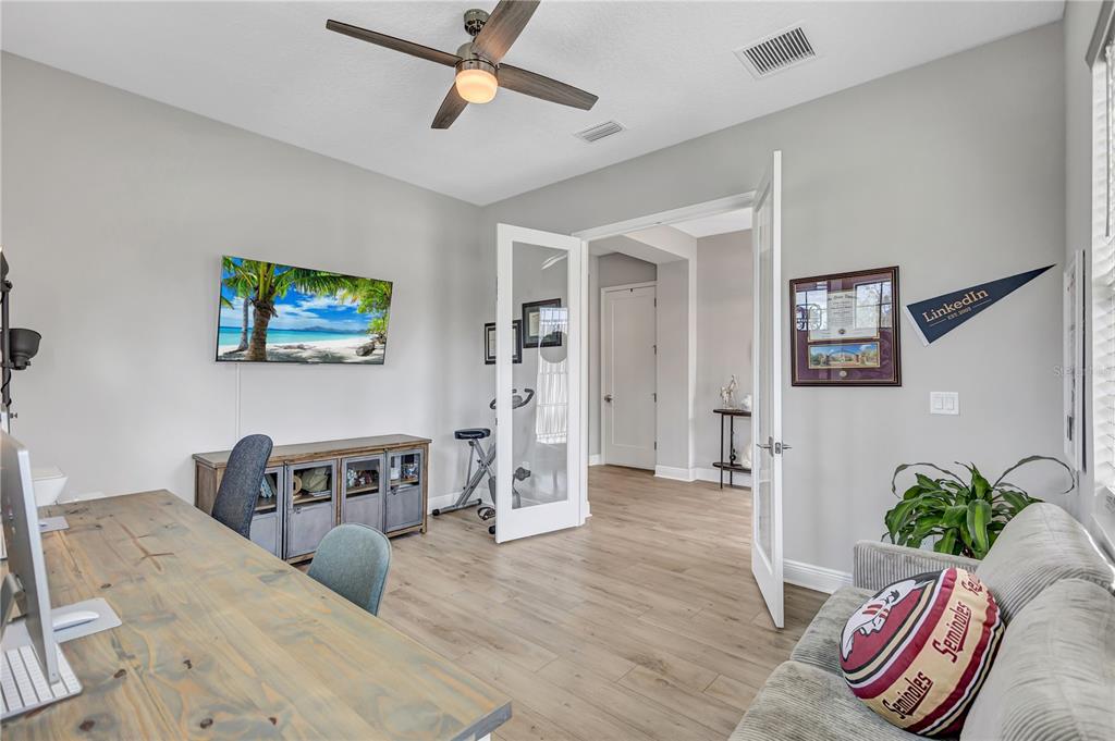 A home office features a wooden desk, a sofa, a ceiling fan, and French doors — 4593 SHORELEAF LOOP, VALRICO, FL