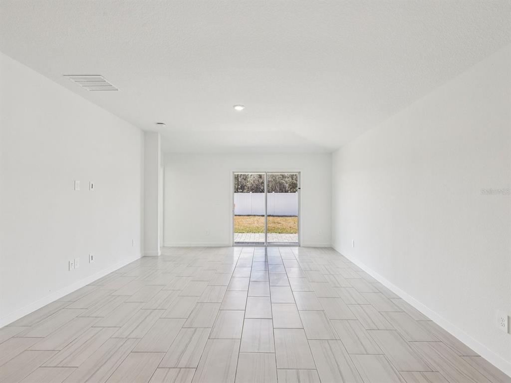 A modern kitchen features white cabinets, a central island, and light wood-look tile flooring — 20 GARNI DRIVE, PALM COAST, FL