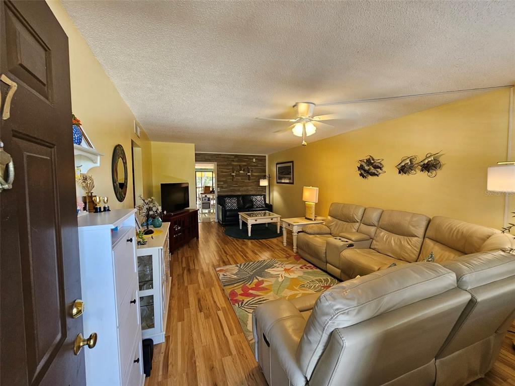 A living room features a television console, a dark sofa, and a glass-topped coffee table — 315 30TH AVENUE W UNIT B307, BRADENTON, FL