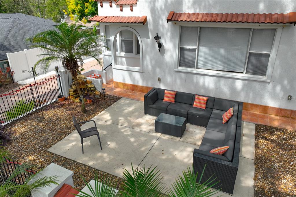 A patio with a sectional sofa, coffee table, and chair sits beside a white house — 229 E 6TH AVENUE, MOUNT DORA, FL