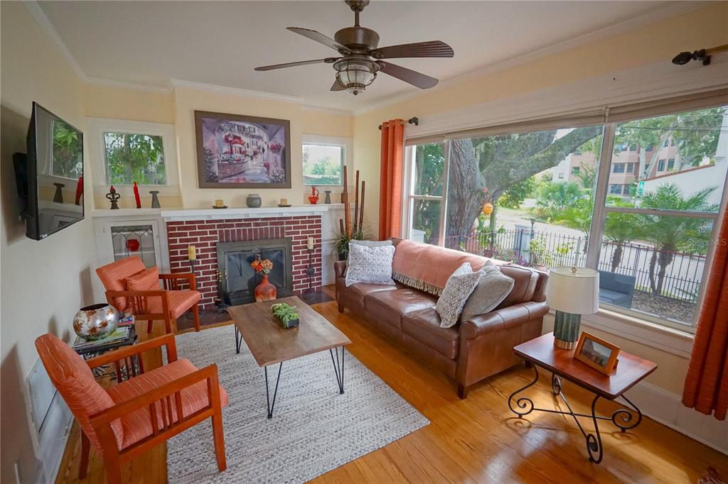 A living room features a brick fireplace, leather sofa, orange chairs, and large windows — 229 E 6TH AVENUE, MOUNT DORA, FL