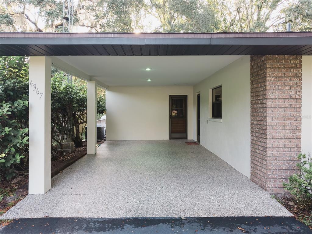 A covered concrete carport features a brick wall, two doorways, and a support pillar — 4367 S US 301, BUSHNELL, FL