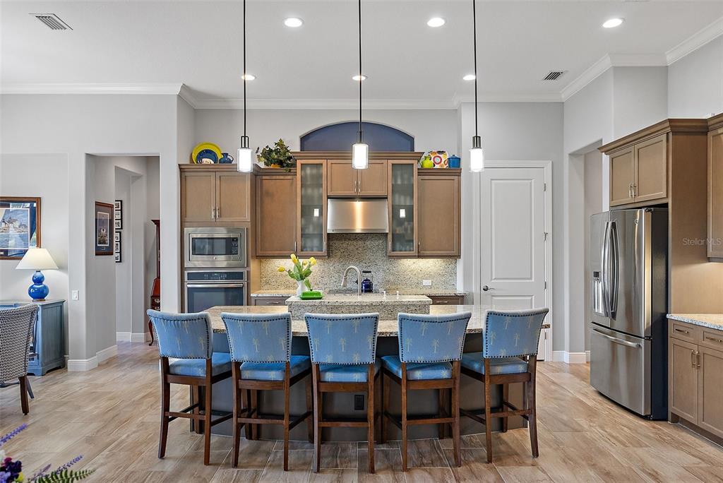 A kitchen with a granite island and stainless steel appliances overlooks a blue living room — 11739 RIVER SHORES TRAIL, PARRISH, FL