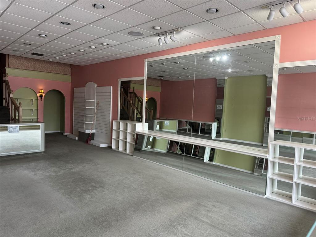 A commercial retail space features pink walls, gray carpeting, mirrored walls, and built-in shelving — 3411 W UNIVERSITY AVENUE, GAINESVILLE, FL
