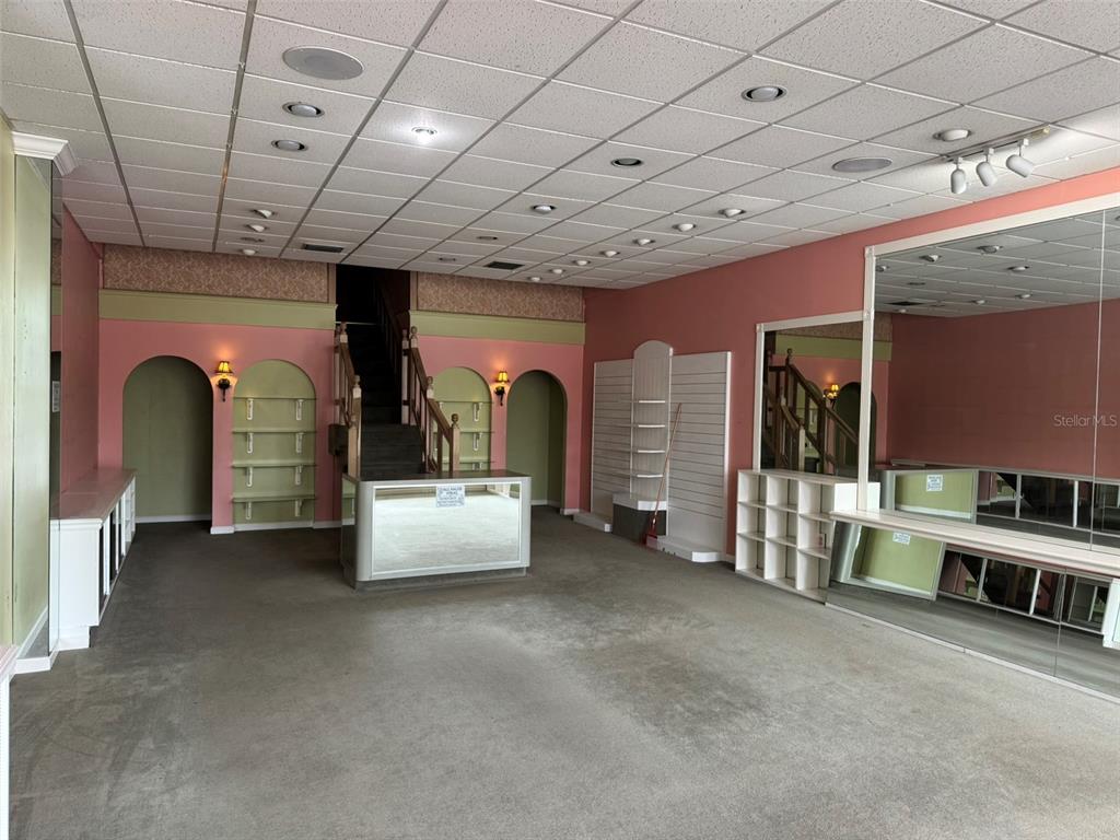 A commercial retail space features pink walls, arched shelving, a central counter, and mirrored walls — 3411 W UNIVERSITY AVENUE, GAINESVILLE, FL