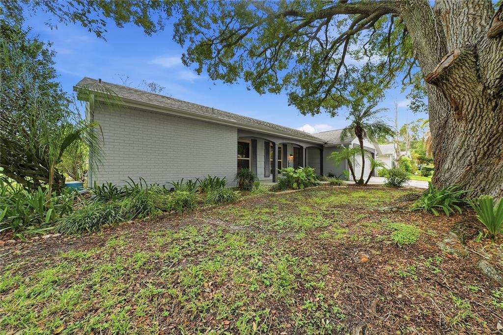 A single-story gray brick house with a large oak tree in the front yard — 12605 RIVER MILL DRIVE, HUDSON, FL