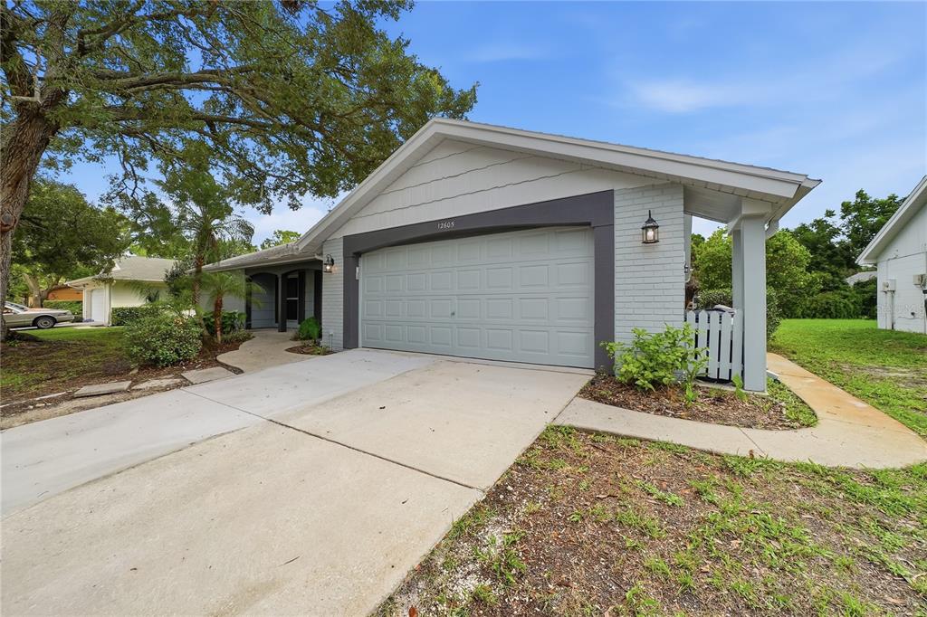 A single-story house with a gray brick facade, a two-car garage, and a concrete driveway — 12605 RIVER MILL DRIVE, HUDSON, FL