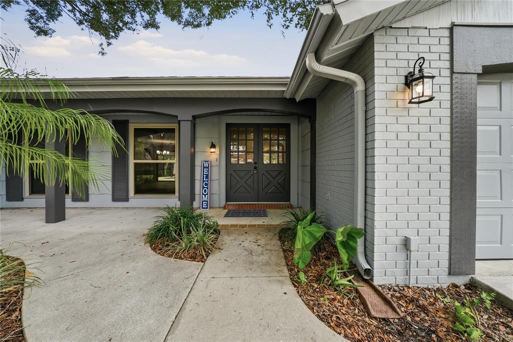 A gray brick house exterior features a covered entryway with double doors and a walkway — 12605 RIVER MILL DRIVE, HUDSON, FL