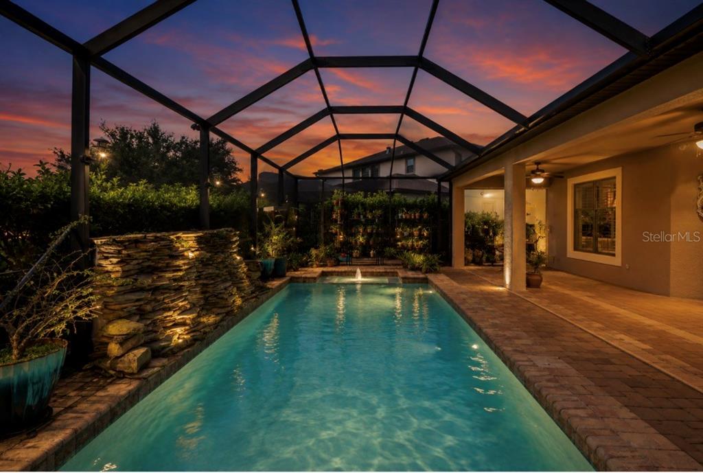 A screened-in swimming pool with a stone water feature and a safety fence — 743 WELLINGTON COURT, OLDSMAR, FL