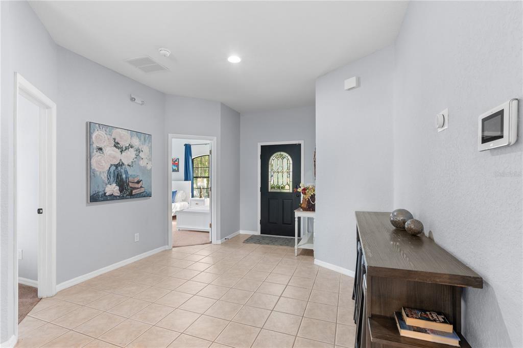A tiled entryway features a black front door, a console table, and wall art — 16813 LAZY BREEZE LOOP, CLERMONT, FL