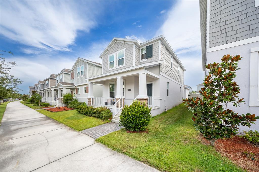 A row of light-colored suburban houses with front porches lines a concrete sidewalk — 1596 CROSS PRAIRIE PARKWAY, KISSIMMEE, FL