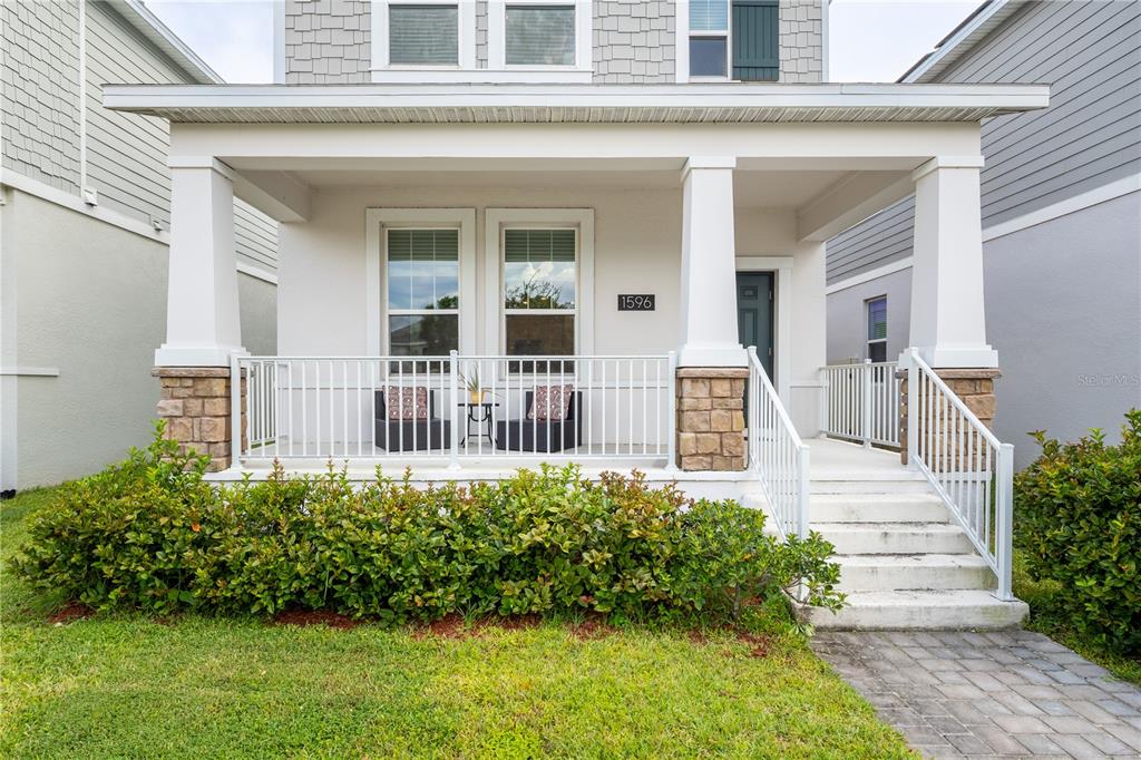 A front porch with white railings and columns sits before a house with light siding — 1596 CROSS PRAIRIE PARKWAY, KISSIMMEE, FL