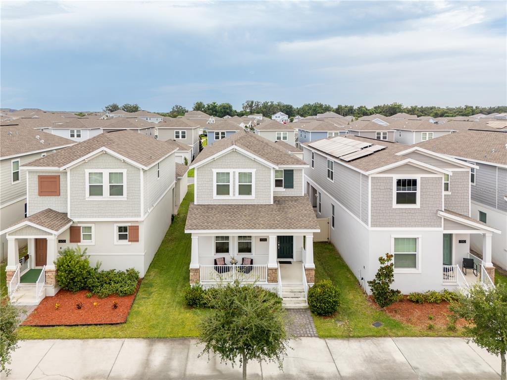 An aerial view shows three two-story suburban houses with light-colored siding and shingled roofs — 1596 CROSS PRAIRIE PARKWAY, KISSIMMEE, FL