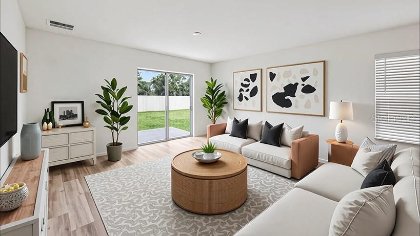 This rendering shows a living room with a sofa, round coffee table, and sliding glass doors — 2106 NE 33RD LANE, OCALA, FL