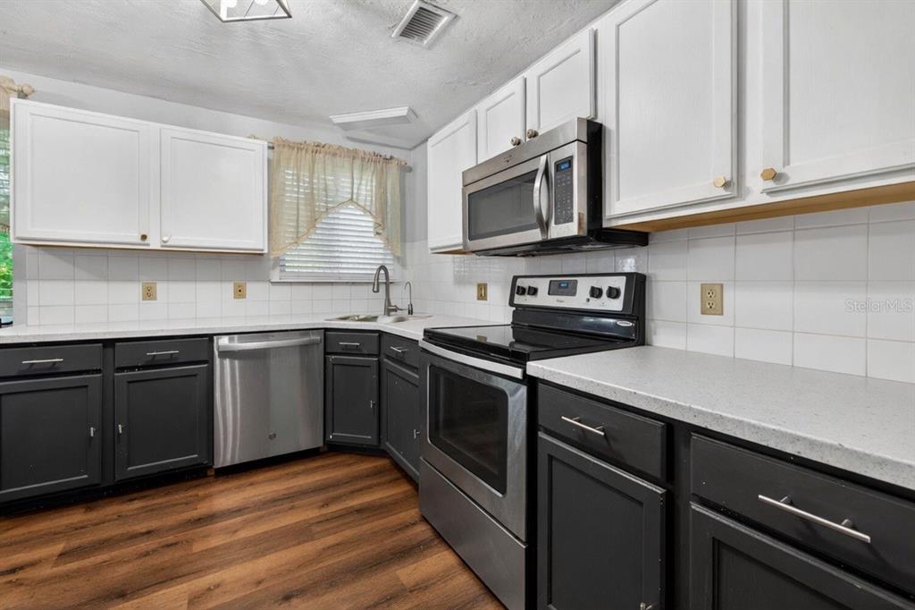 A living room features a sectional sofa, a white coffee table, and wood flooring — 1213 55TH STREET S, GULFPORT, FL