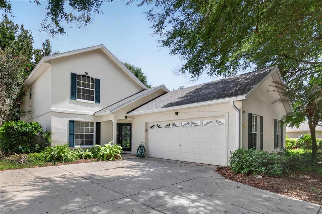 A two-story house with a white stucco exterior, blue shutters, and an attached two-car garage — 4875 ABACO DRIVE, TAVARES, FL