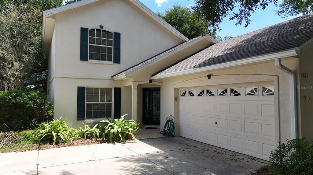 A two-story house with a white stucco exterior, dark shutters, and an attached two-car garage — 4875 ABACO DRIVE, TAVARES, FL