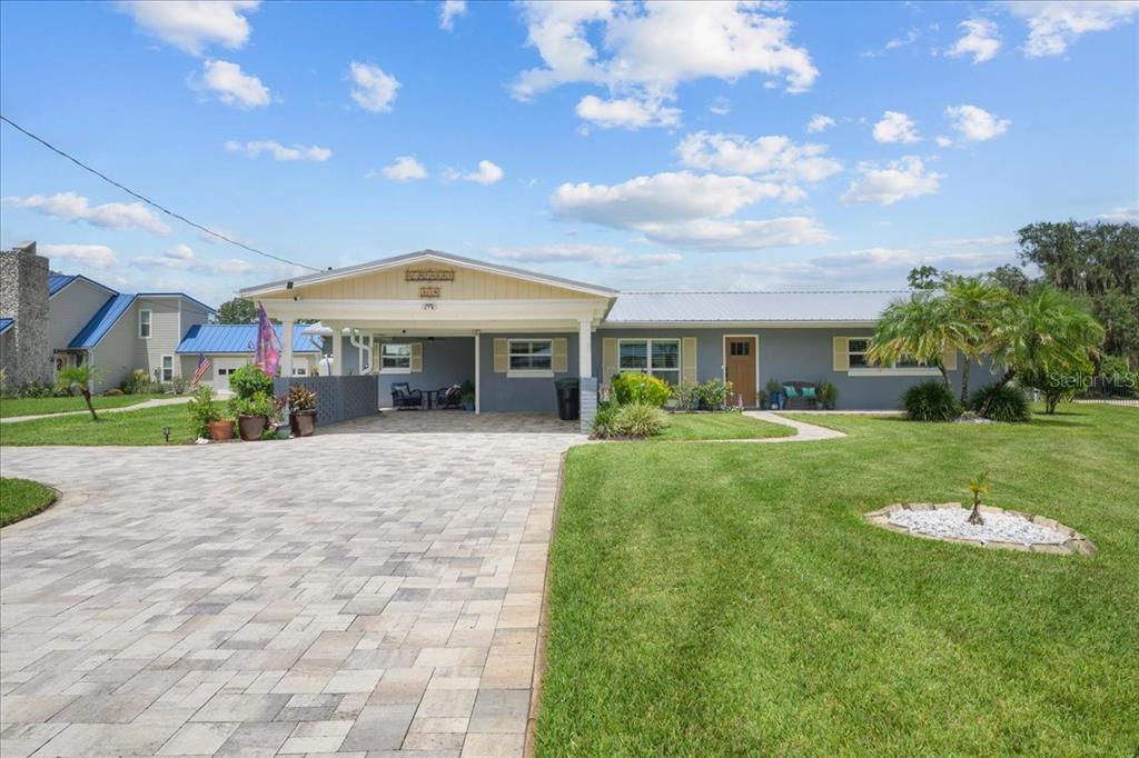 A single-story house with a paved driveway, carport, and a large front lawn — 209 RIVER DRIVE, EAST PALATKA, FL