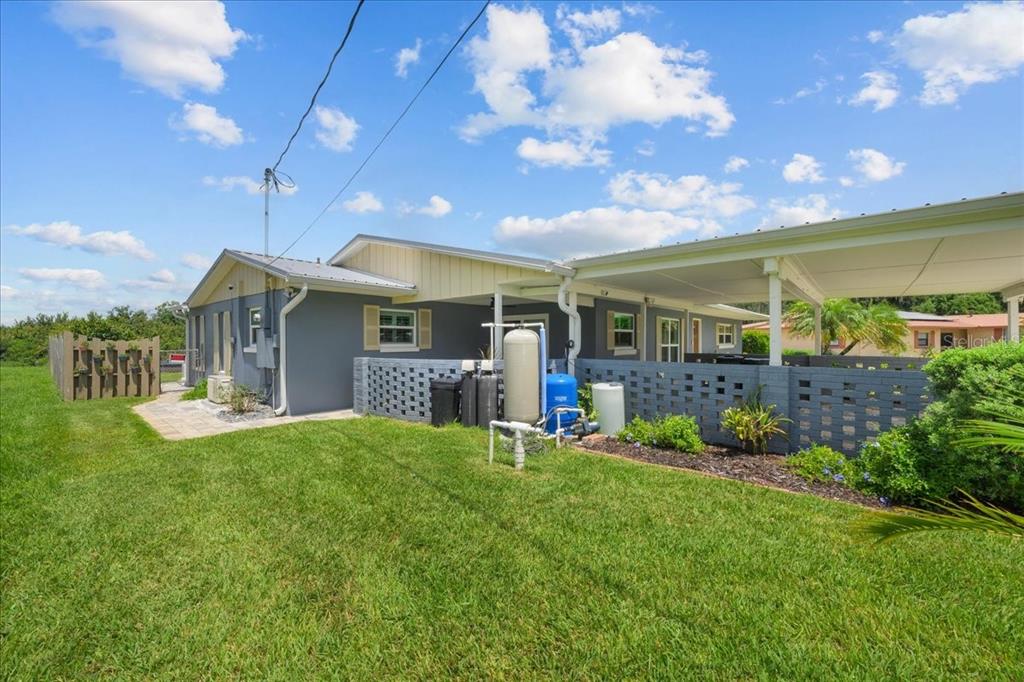 The exterior of a house features a gray wall, a carport, and a water system — 209 RIVER DRIVE, EAST PALATKA, FL