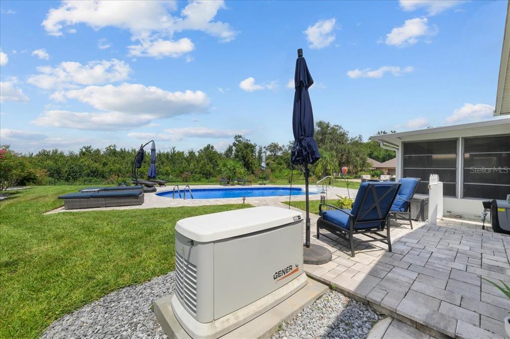 A backyard patio features a Generac generator, a swimming pool, and lounge chairs on pavers — 209 RIVER DRIVE, EAST PALATKA, FL
