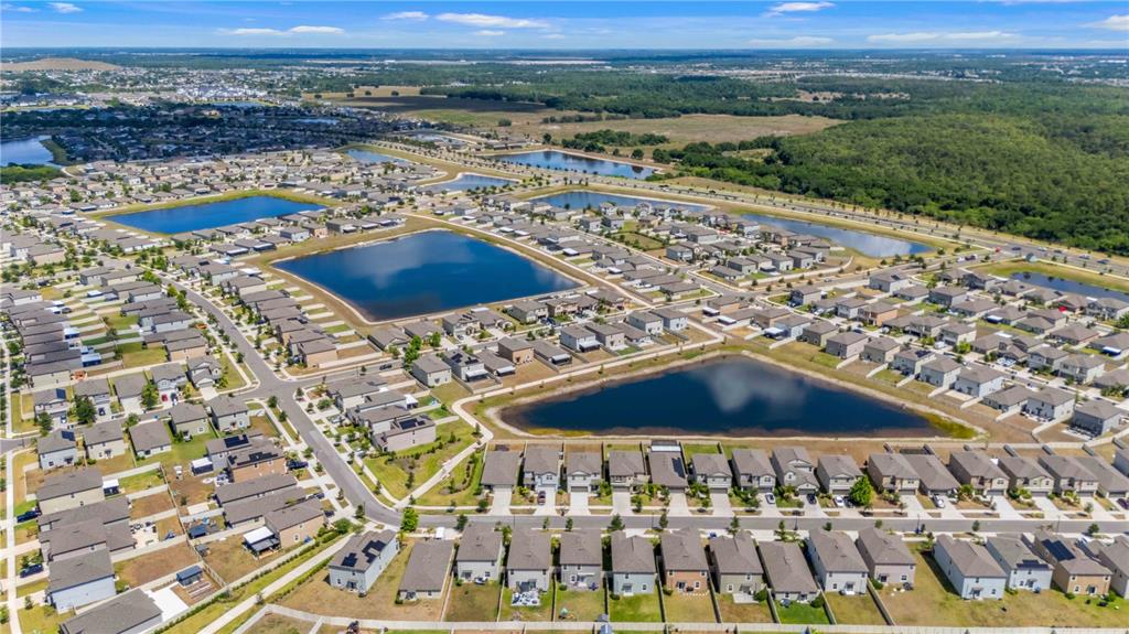 An aerial view shows a suburban neighborhood with multiple retention ponds and rows of houses — 9440 LEMON DROP LOOP, SUN CITY CENTER, FL
