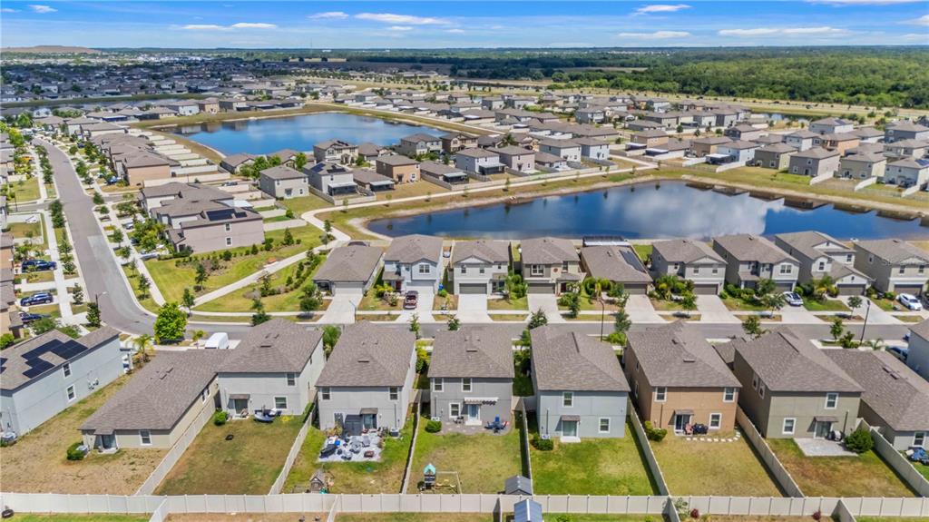 An aerial view shows suburban houses with fenced backyards situated near two large retention ponds — 9440 LEMON DROP LOOP, SUN CITY CENTER, FL