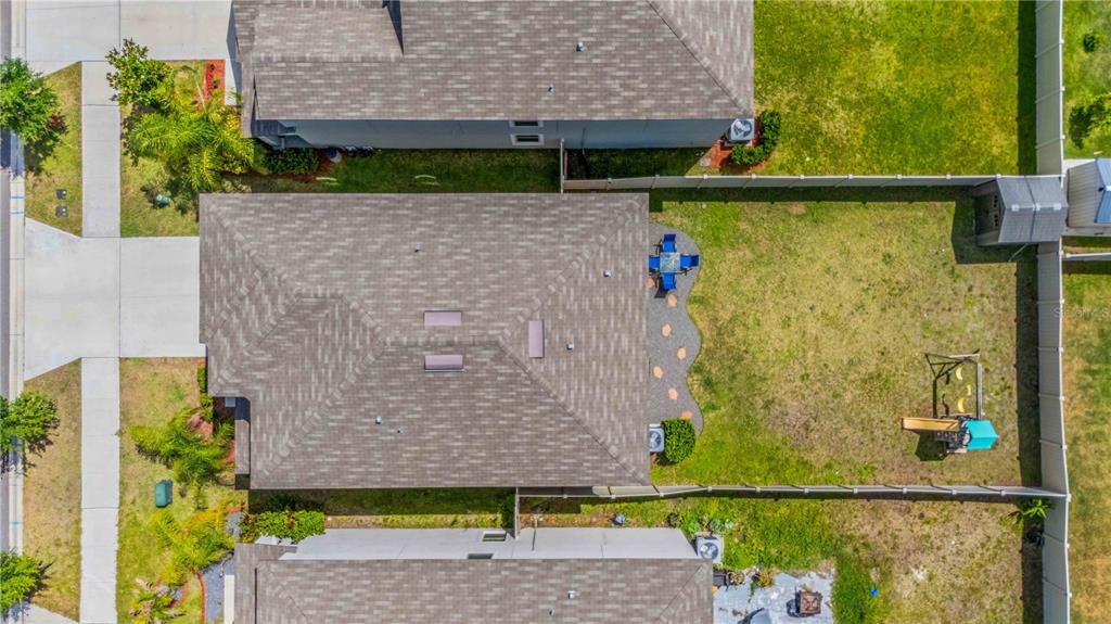 An aerial view shows a house with a shingled roof, backyard patio, and playground equipment — 9440 LEMON DROP LOOP, SUN CITY CENTER, FL