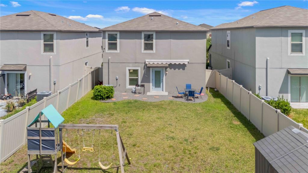 The backyard of a two-story house features a lawn, a swing set, and a patio — 9440 LEMON DROP LOOP, SUN CITY CENTER, FL