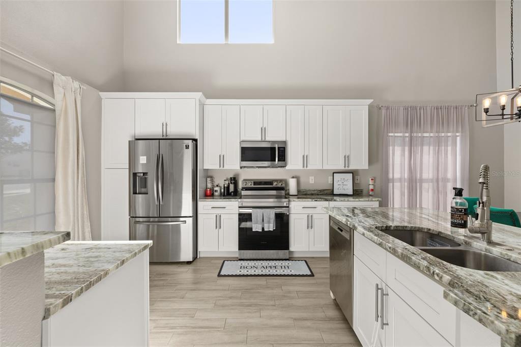 A kitchen with white cabinets, stainless steel appliances, and a marble-patterned island countertop — 2313 DUNCAN TRAIL, CLERMONT, FL