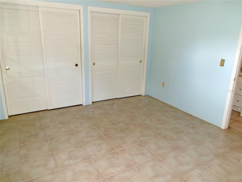 A room with light blue walls, tiled flooring, and two sets of white louvered closet doors — 12709 CLOCK TOWER PARKWAY, HUDSON, FL