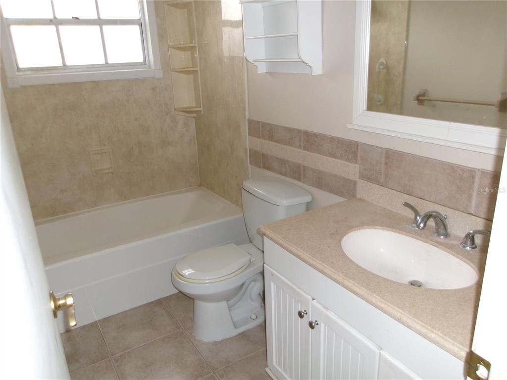 A bathroom features a white vanity, a toilet, and a bathtub with tiled walls — 12709 CLOCK TOWER PARKWAY, HUDSON, FL