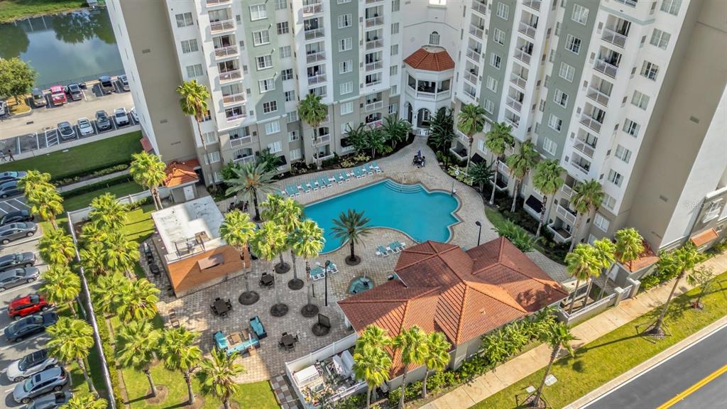 An aerial view shows a multi-story apartment building with a pool and courtyard area — 7395 UNIVERSAL BLVD UNIT 402, ORLANDO, FL