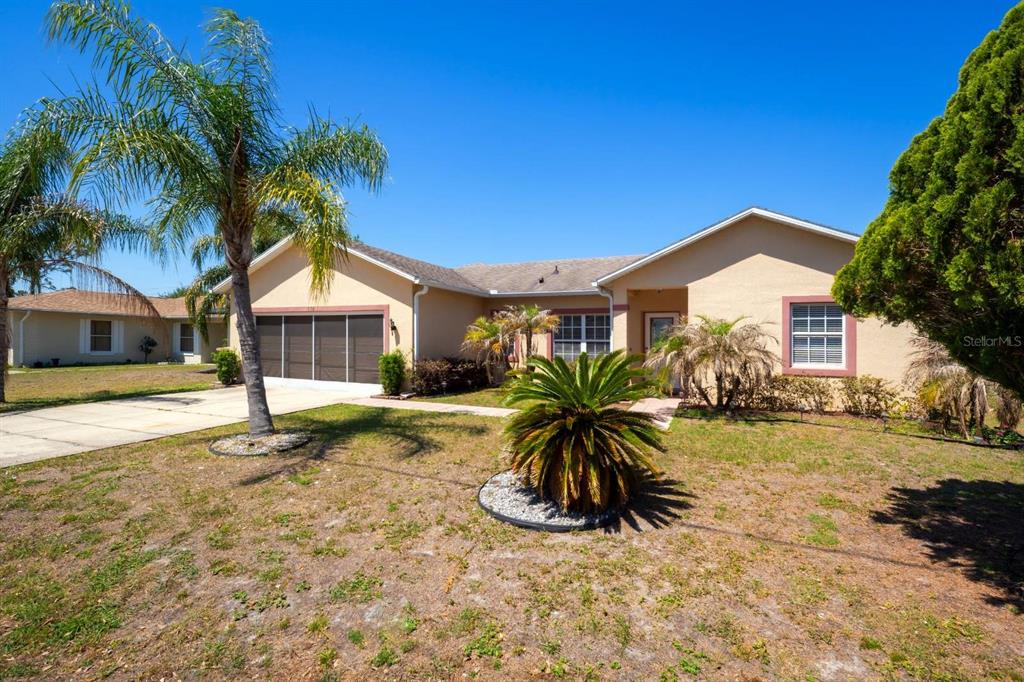 A single-story house with a tan stucco exterior, a two-car garage, and a landscaped yard — 526 MARICOPA DRIVE, KISSIMMEE, FL