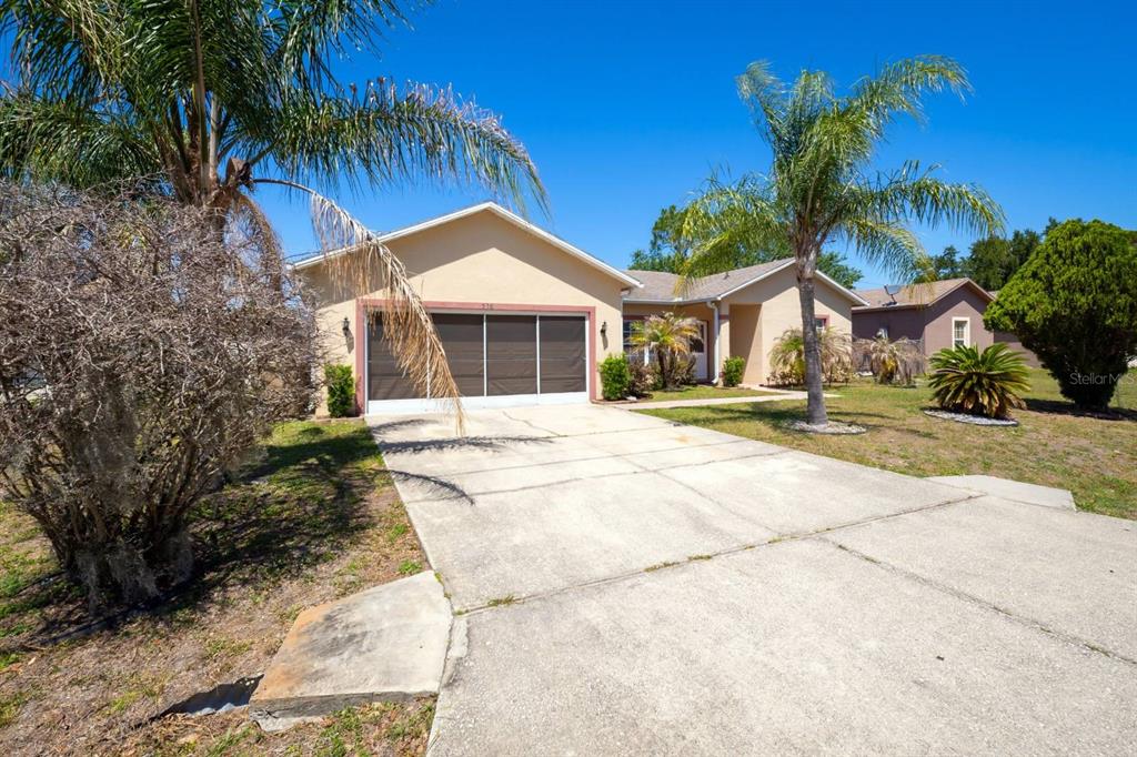 A single-story house with a concrete driveway, a garage, and palm trees in the front yard — 526 MARICOPA DRIVE, KISSIMMEE, FL