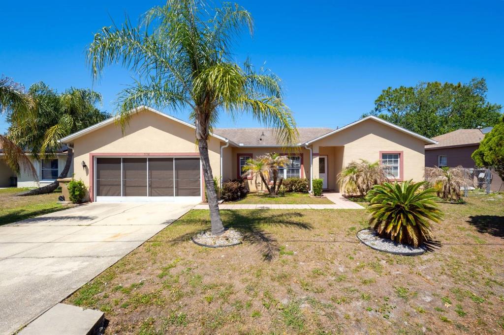 A single-story house with a tan exterior, a two-car garage, and a front yard palm tree — 526 MARICOPA DRIVE, KISSIMMEE, FL