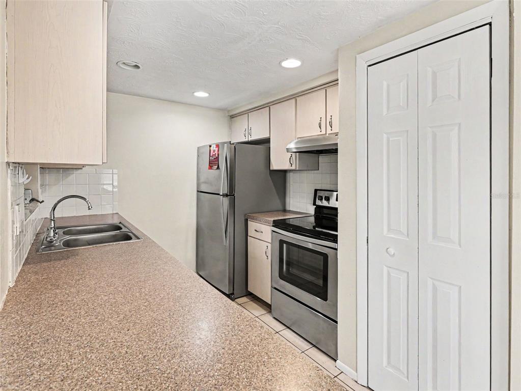 A kitchen features stainless steel appliances, light-colored cabinets, and a long laminate countertop — 3609 TRUMAN DRIVE, HOLIDAY, FL