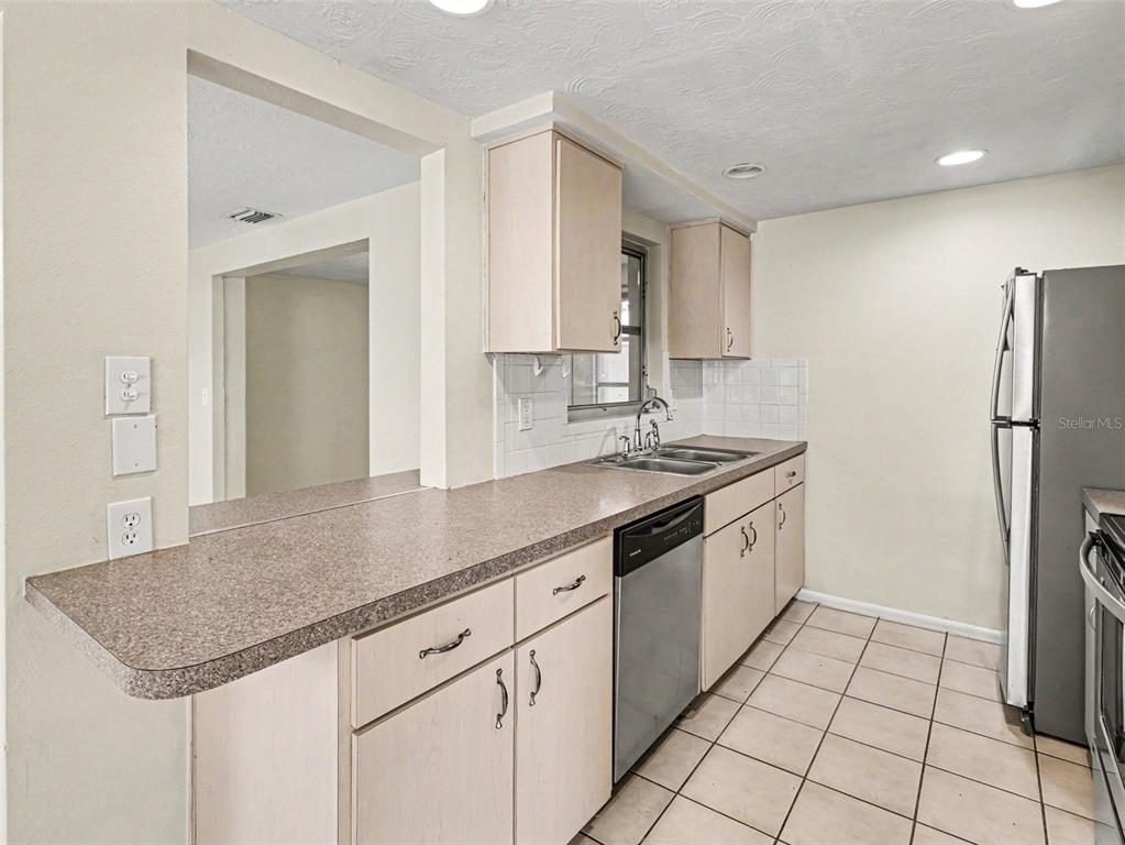 A kitchen with light wood cabinets, laminate countertops, stainless steel appliances, and tiled flooring — 3609 TRUMAN DRIVE, HOLIDAY, FL