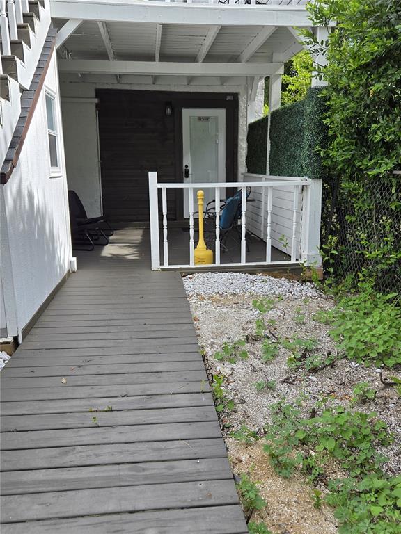 A wooden walkway leads to a covered patio with a white railing and a door — 1690 S 10TH STREET UNIT B, HAINES CITY, FL