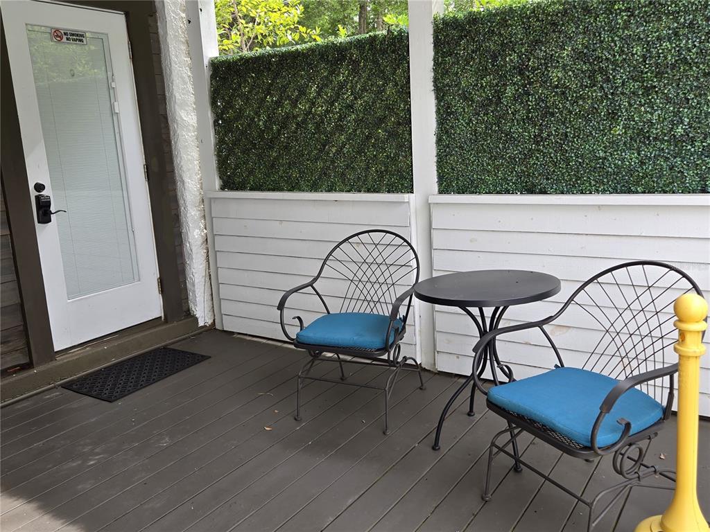 A wooden deck features two chairs with blue cushions, a small table, and privacy screens — 1690 S 10TH STREET UNIT B, HAINES CITY, FL
