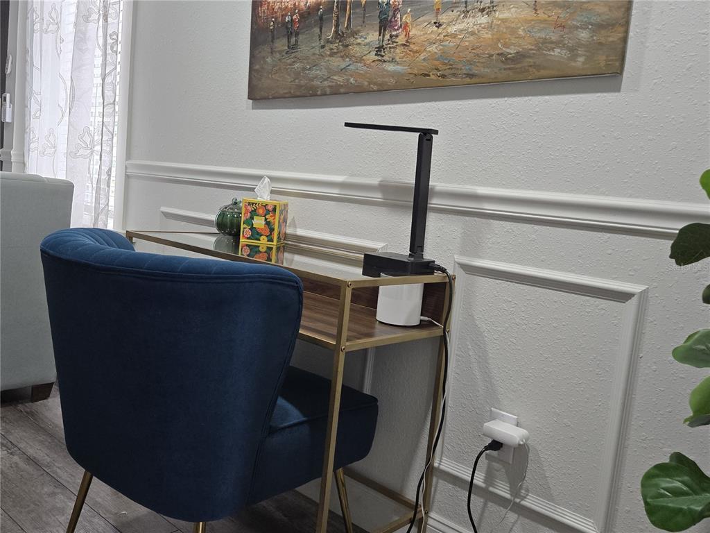 A blue velvet chair sits at a glass-topped desk with a lamp against a paneled wall — 1690 S 10TH STREET UNIT B, HAINES CITY, FL