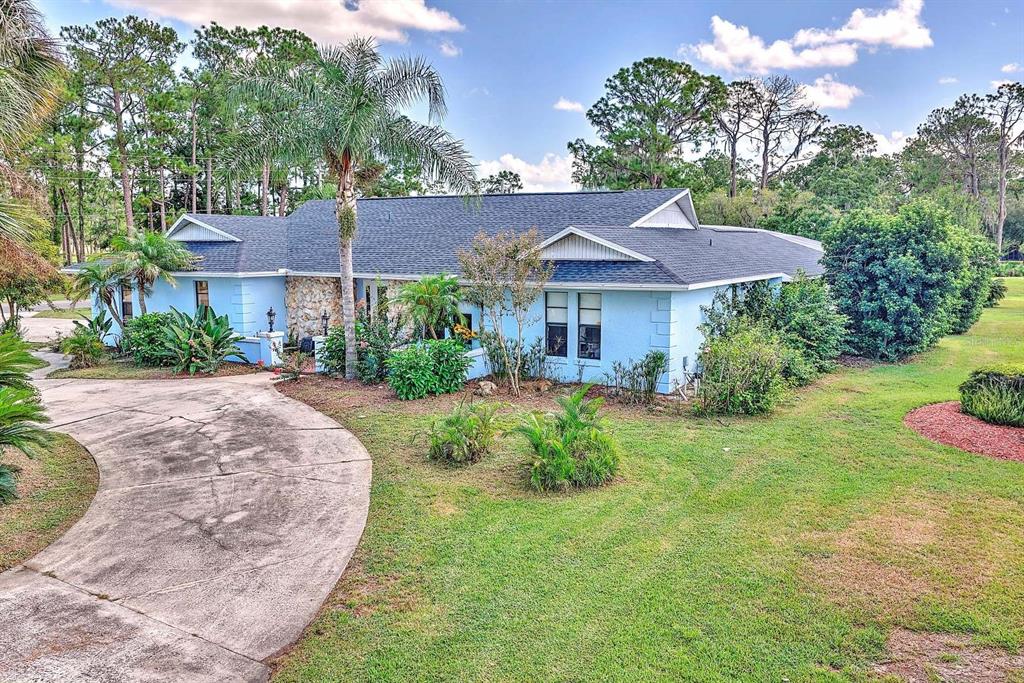 A light blue single-story house with a stone facade and a curved concrete driveway — 4012 SUNRISE DRIVE, SEBRING, FL