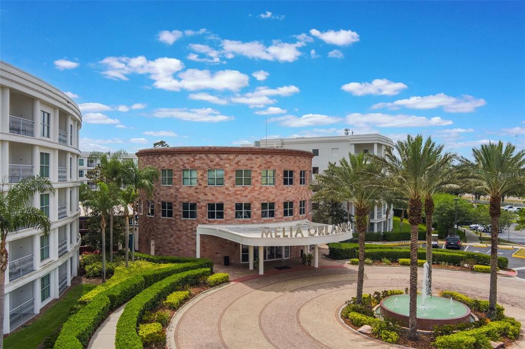 An exterior view of a circular brick building with a fountain and palm trees — 225 CELEBRATION PLACE UNIT 401, KISSIMMEE, FL