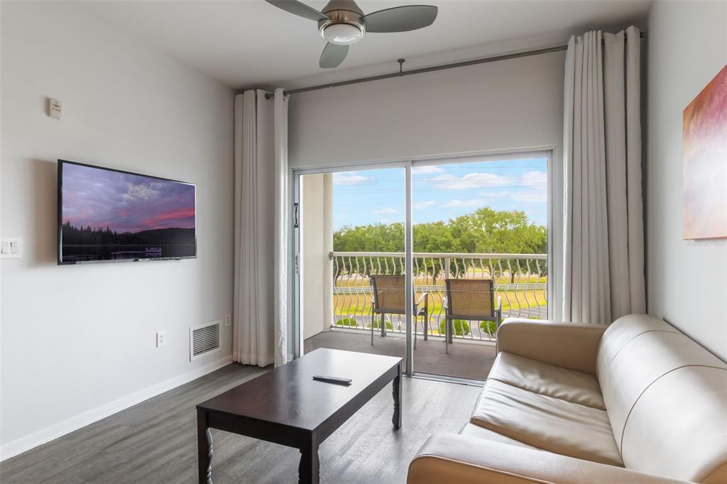A living room features a wall-mounted television, a coffee table, a sofa, and a balcony — 225 CELEBRATION PLACE UNIT 401, KISSIMMEE, FL