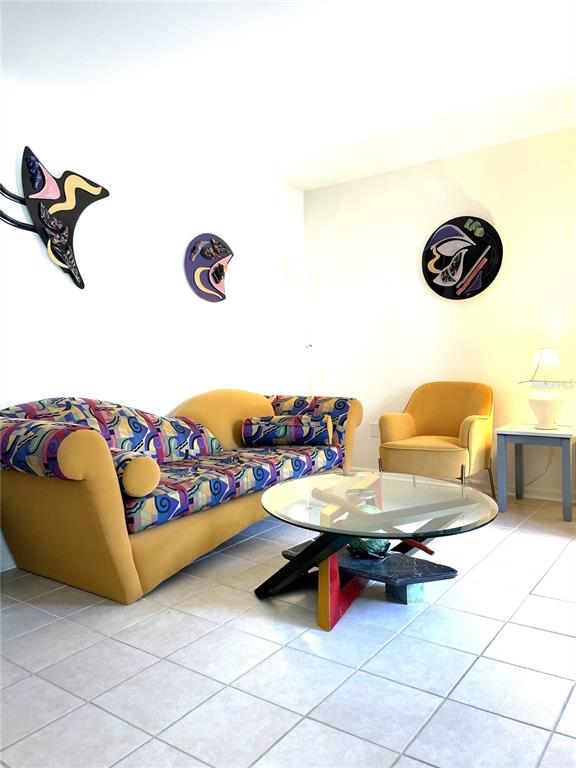 A living room features a patterned sofa, a yellow armchair, and a glass-topped coffee table — 19 LOVETT STREET, ST AUGUSTINE, FL