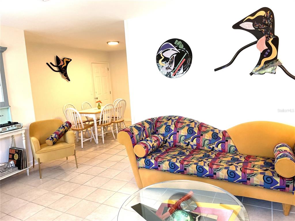 A living room features a patterned sofa, a yellow armchair, and a dining area beyond — 19 LOVETT STREET, ST AUGUSTINE, FL