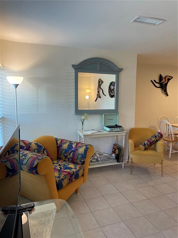 A living room features a patterned armchair, a yellow accent chair, and a console table — 19 LOVETT STREET, ST AUGUSTINE, FL