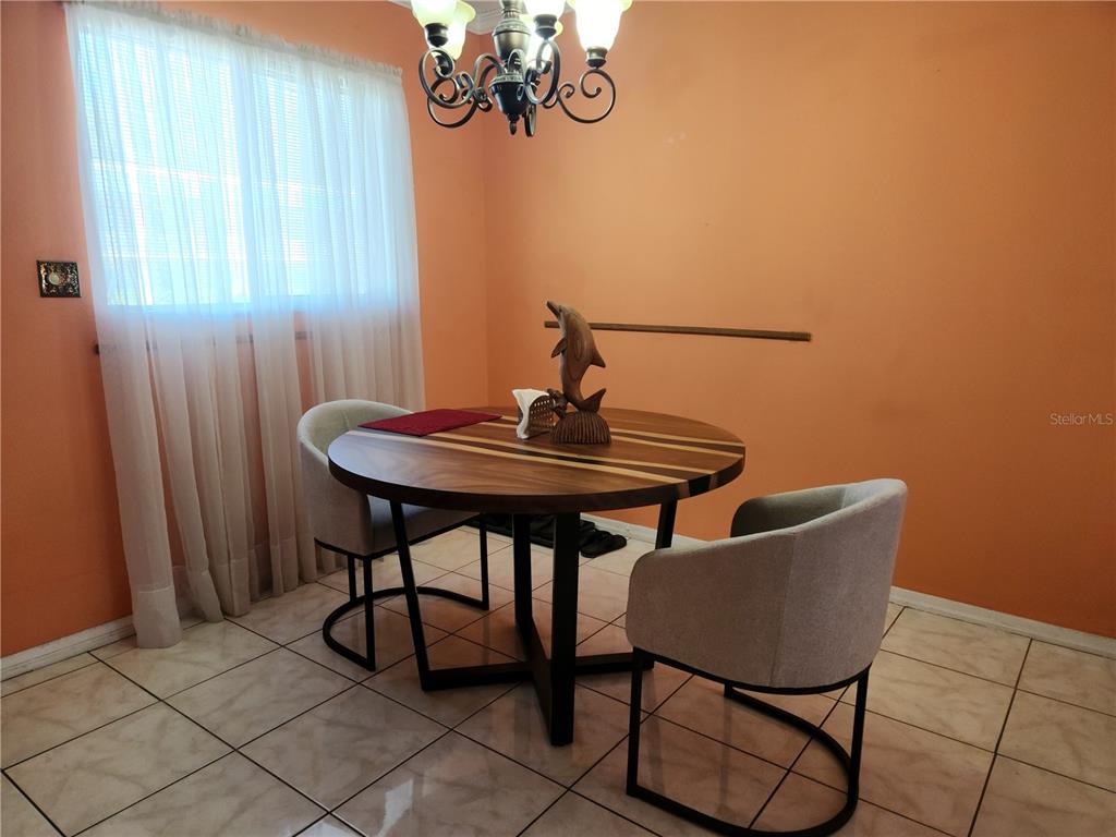 A dining area features a round wooden table, two upholstered chairs, and a chandelier — 2001 GREENBRIAR BOULEVARD UNIT 6, CLEARWATER, FL